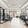 The fitness center at our apartments in Prosper, featuring wood grain floor paneling, treadmills, and other machines. 