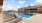 The pool area at our apartments for rent in Prosper, TX, featuring beach chairs and a shade structure.