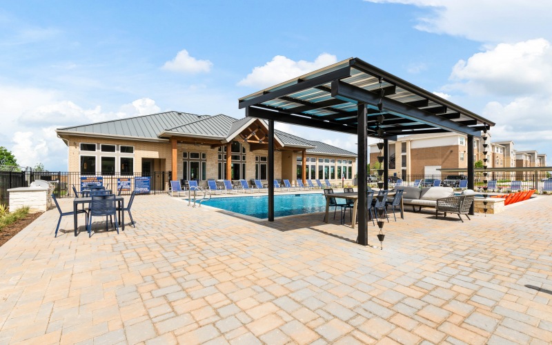 The pool area at our apartments for rent in Prosper, TX, featuring beach chairs and a shade structure.