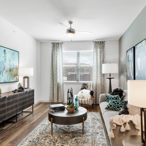 Model living room at our apartments for rent in Prosper, TX, featuring wood grain floor paneling and couches.	