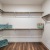 Walk in closet at our apartments for rent in Prosper, featuring wood grain floor paneling and shelving racks.